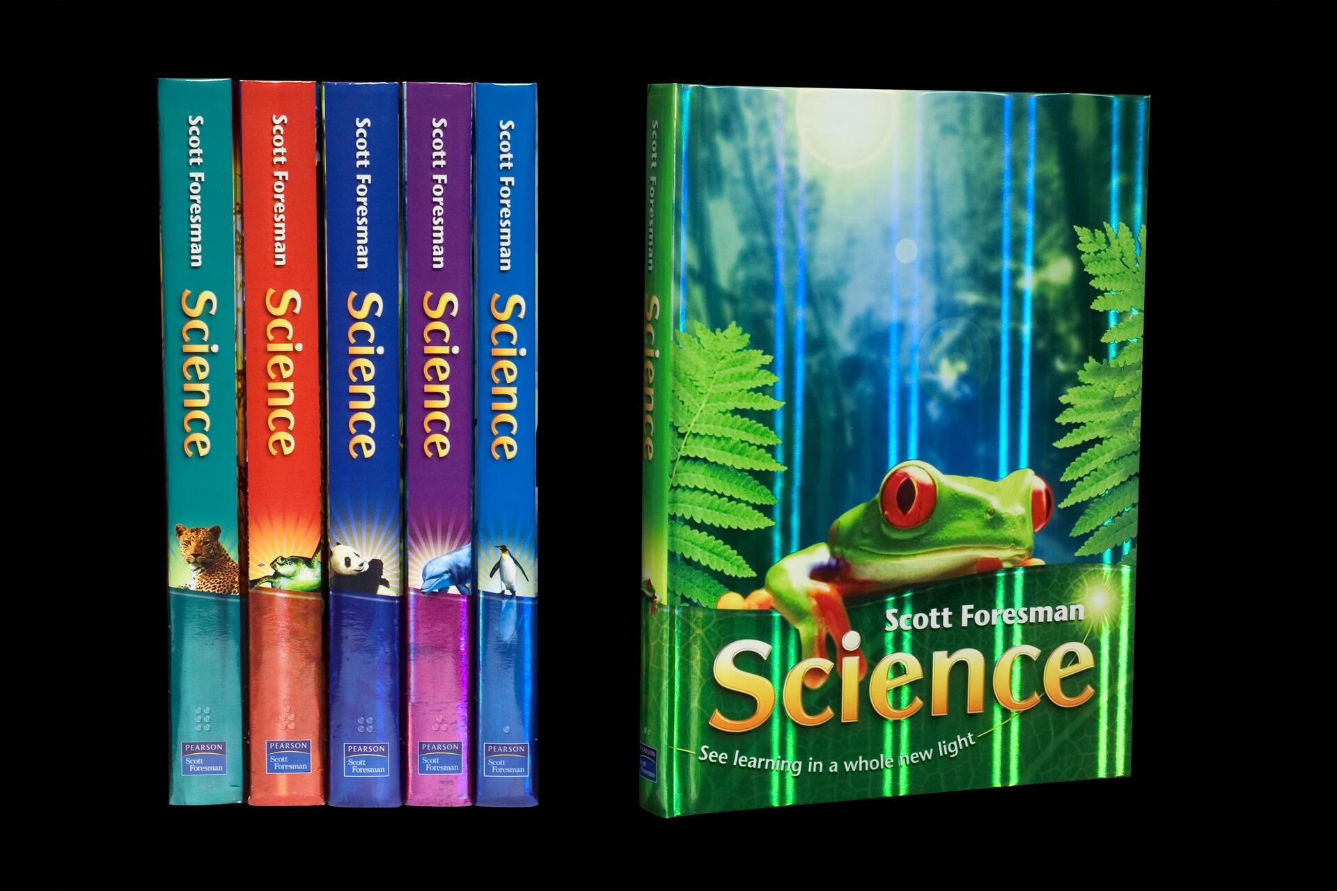 Five colorful science textbooks by Scott Foresman, each with a distinct animal on the spine. A sixth larger book cover displays a vibrant image of a red-eyed tree frog amidst green foliage and blue light beams.