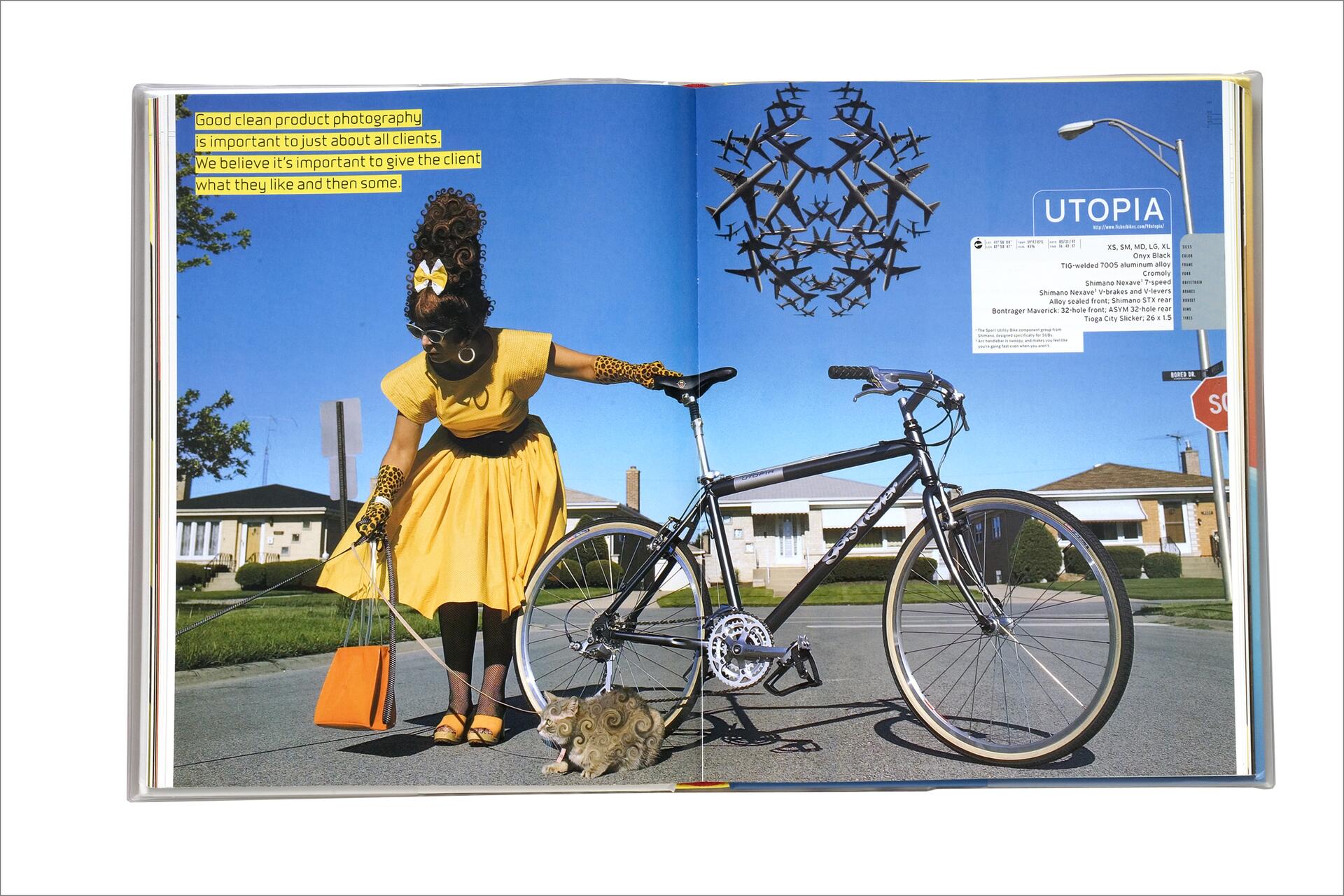 A person in a yellow dress and large hair bow leans towards a whimsical, curled cat beside a bicycle on a suburban street. The sky is blue, and a flock of birds forms a circular shape above.