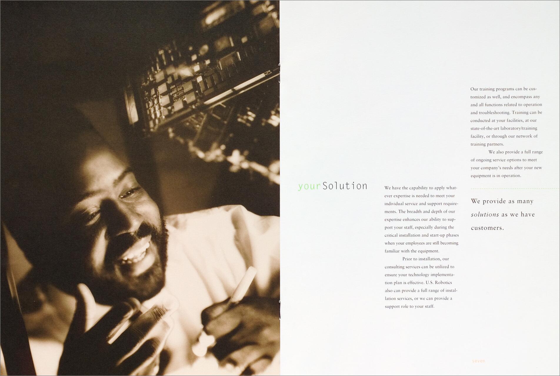 Smiling man with a beard writing on paper next to a large circuit board. The left side is a sepia-toned photograph; the right features text about solutions and training programs.