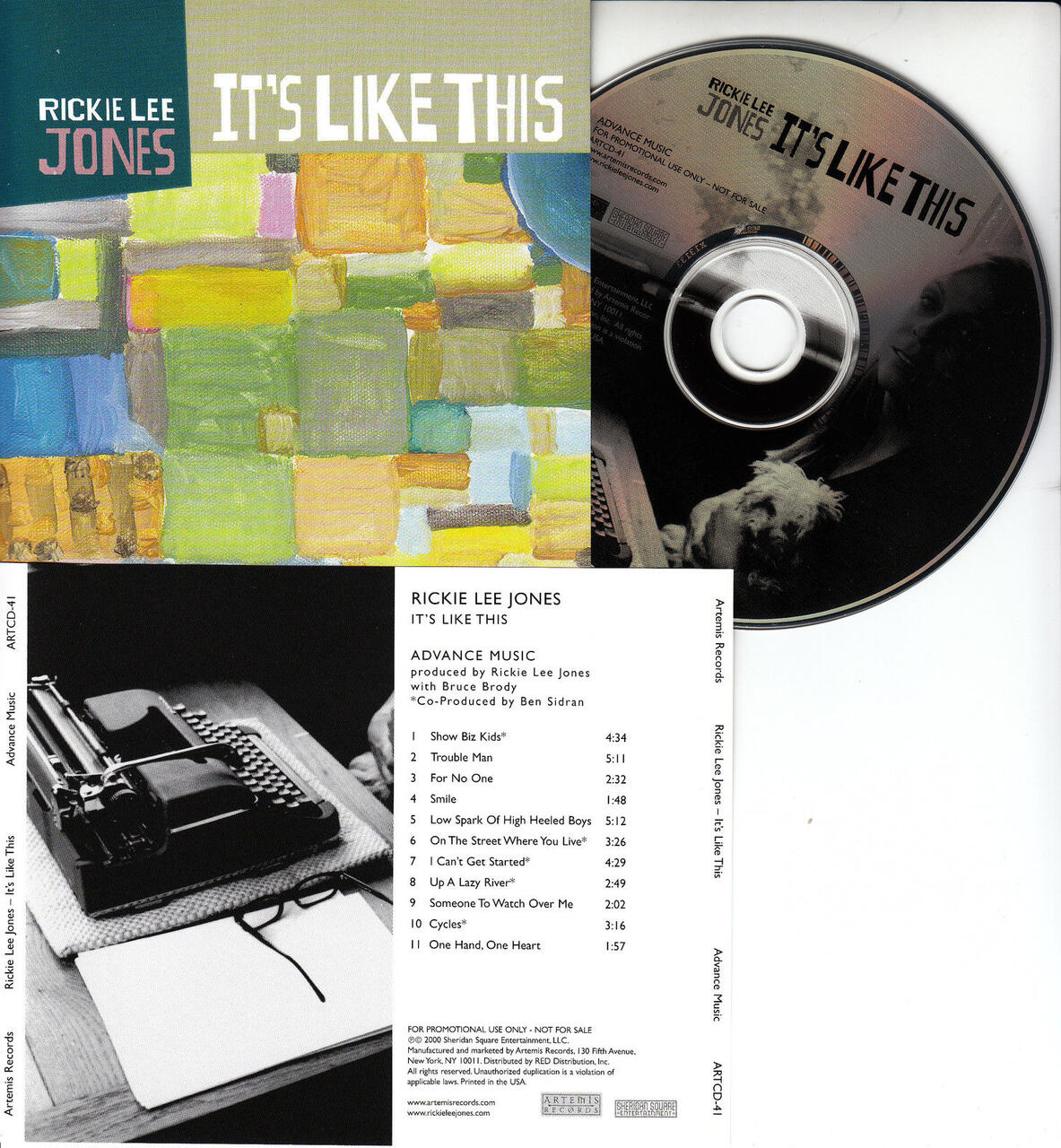 Album cover and CD for "It's Like This" by Rickie Lee Jones. The cover has a colorful, abstract square pattern. The CD features a black-and-white photo of a person with a dog. The tracklist is displayed on a white sheet with a typewriter.