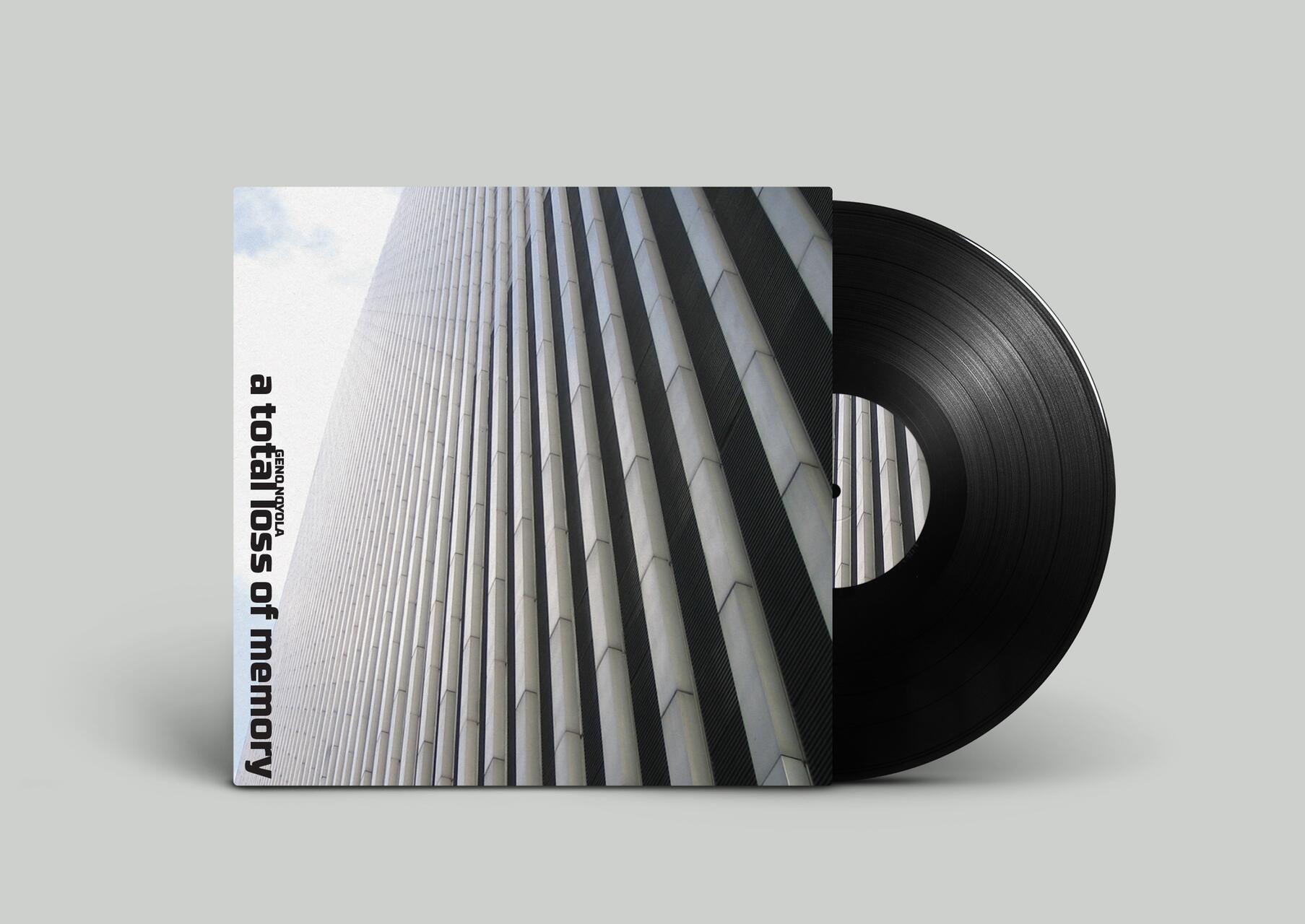 Vinyl record partially removed from its sleeve featuring an architectural photo of a tall, textured building with the title "a total loss of memory" on a gray background.
