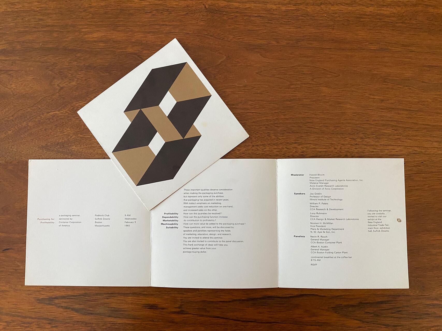 Open brochure on wooden table with geometric art print on top. Brochure displays event information and names in black text on white background. Geometric art features interlocking shapes in black and brown.