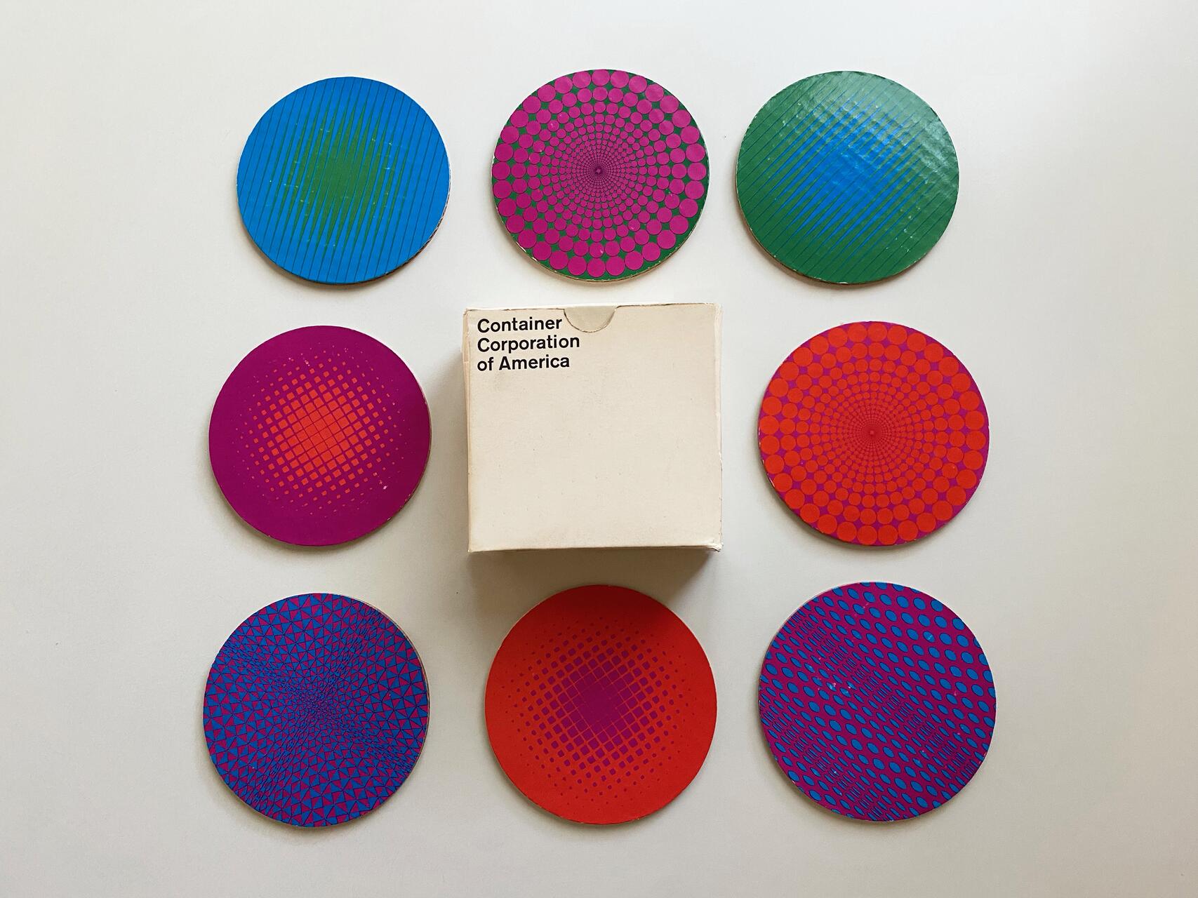 Colorful coasters with geometric patterns arranged around a small box labeled "Container Corporation of America" on a white surface.