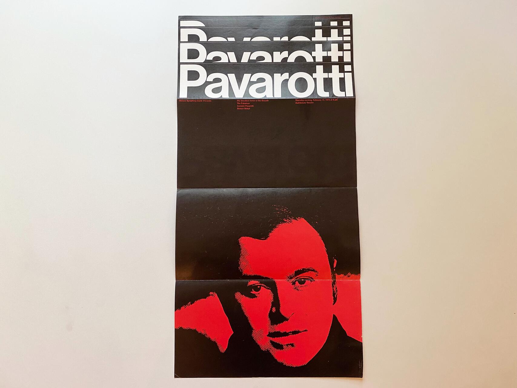 Folded poster with "Pavarotti" text in bold white letters at the top. It features a black and red image of a man's face, partially visible due to the folds. Background is plain white.