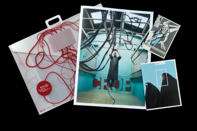 A collage featuring a plastic folder with red strings, a central photograph of a person under a ceiling of cables in a blue room with "CROP" on the wall, and two smaller abstract artworks.