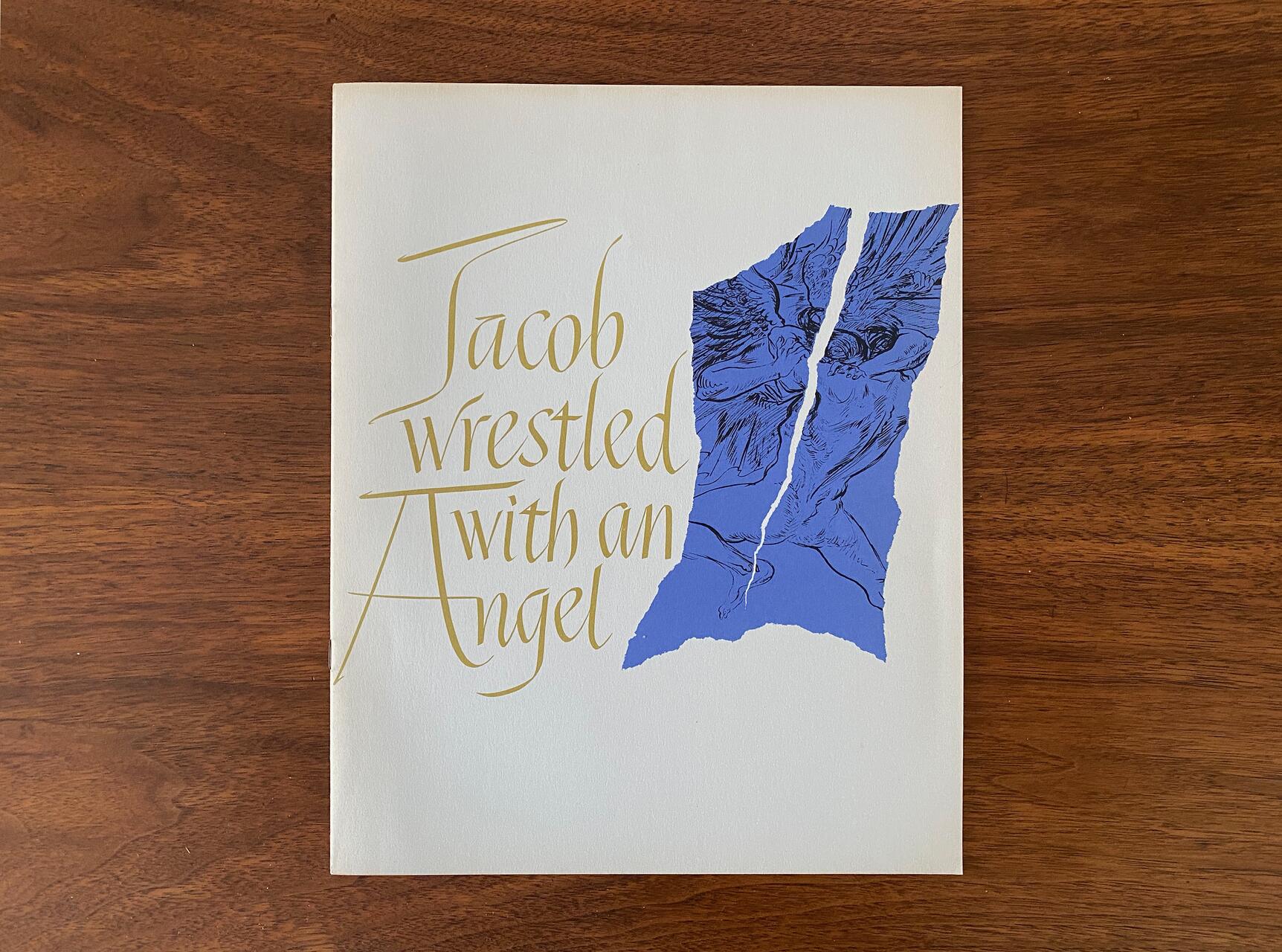 Cream-colored poster with elegant, gold text reading "Jacob wrestled with an Angel" beside a torn, blue illustration depicting figures grappling. Set on a wooden surface.