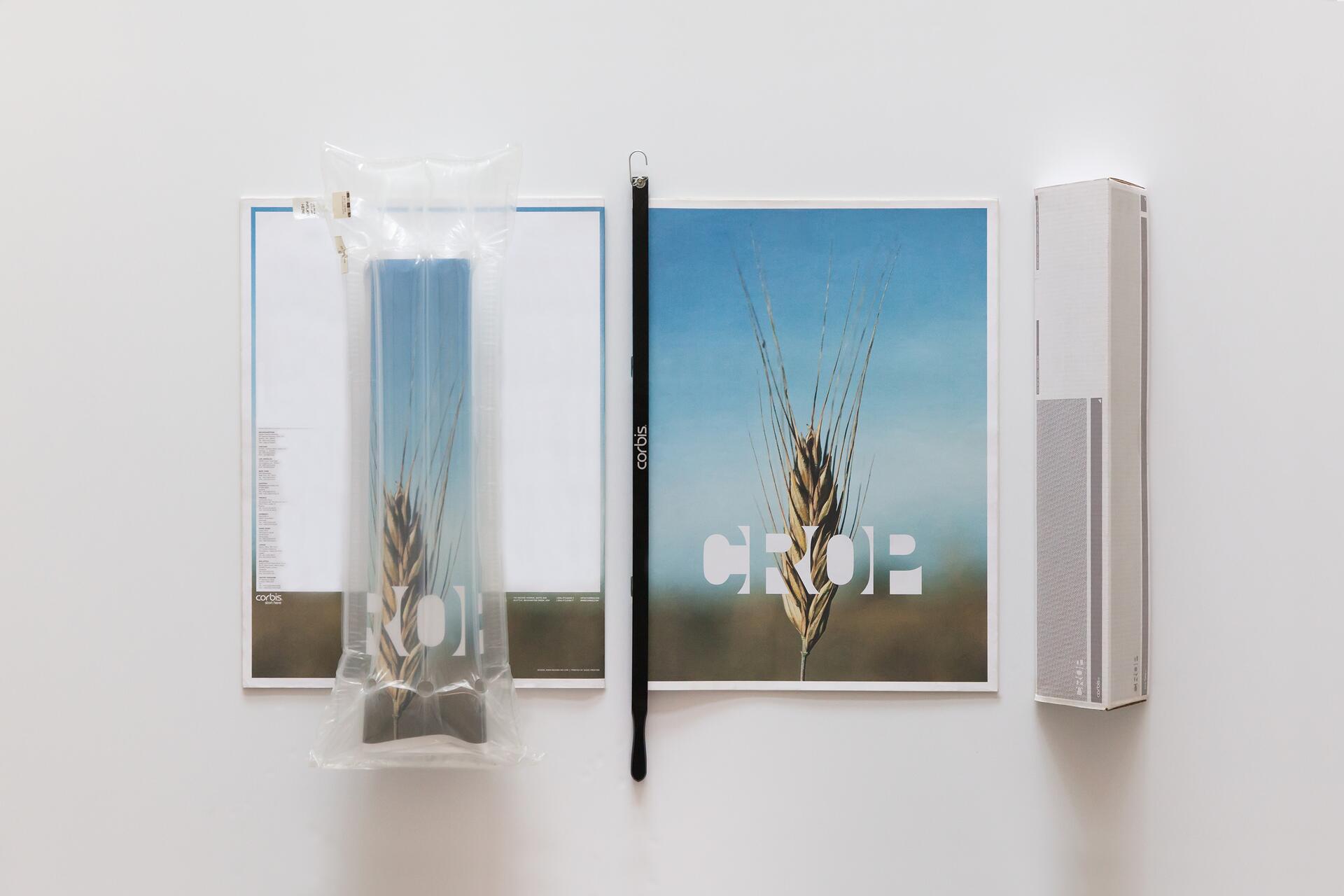 Packaging and branding materials for a product labeled "CROP," featuring an image of wheat against a blue sky. Includes a poster, a protective bag, a pen, and a rectangular box, all arranged on a white background.