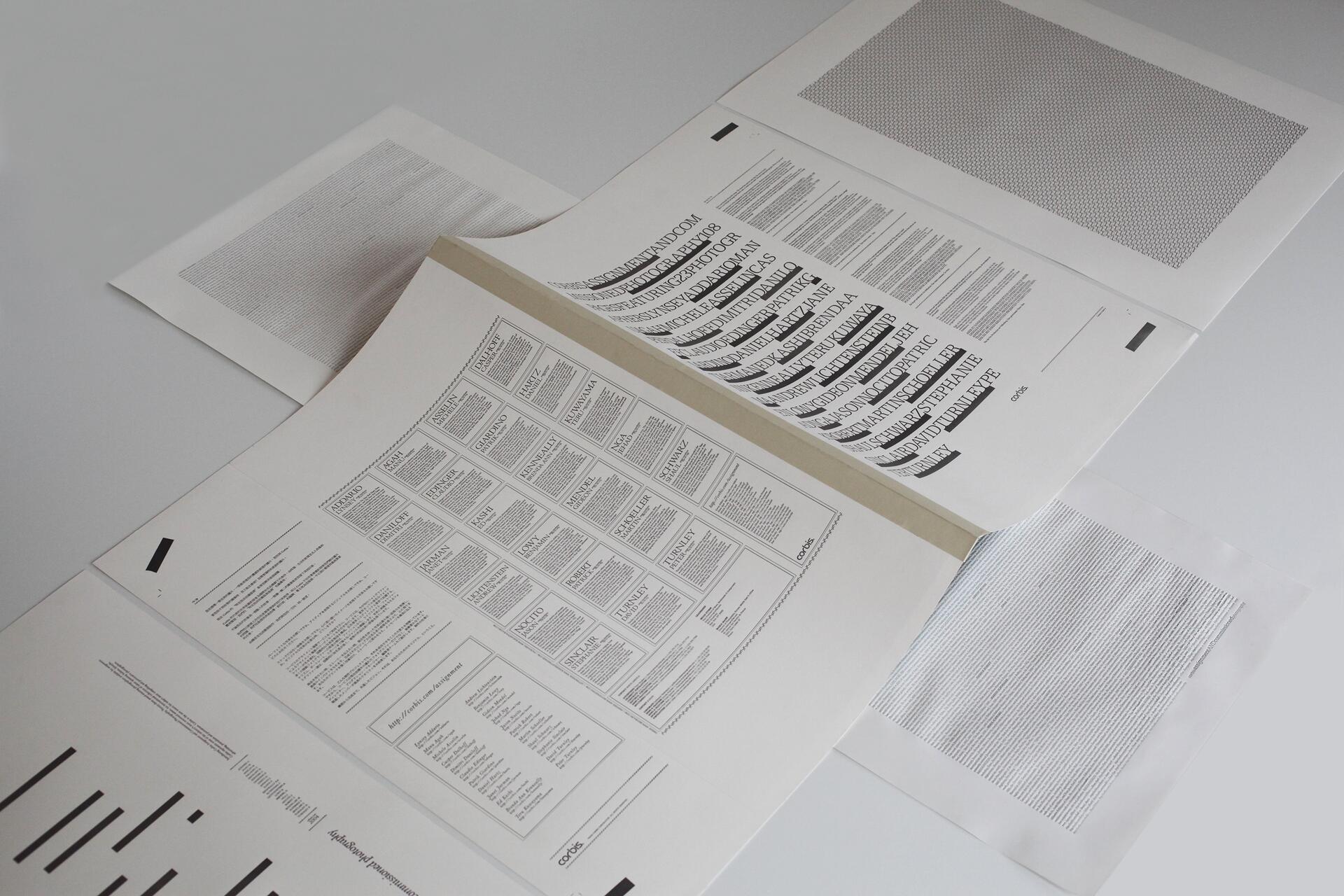 Open book with black and white text and diagrams on a white background, surrounded by additional sheets featuring text patterns and graphical elements.