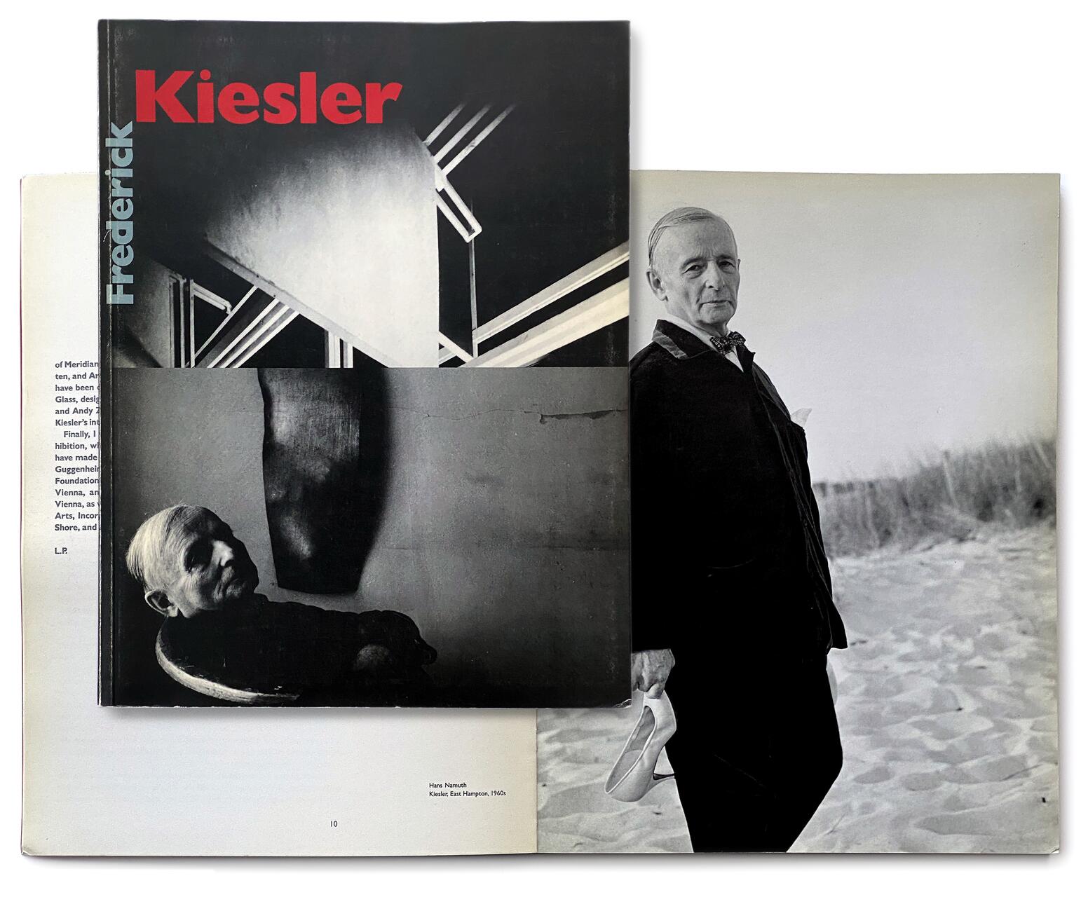 A book with a black and white cover titled "Frederick Kiesler" lies open, overlaying a large photography book displaying a black and white portrait of an older man standing on a beach holding shoes.