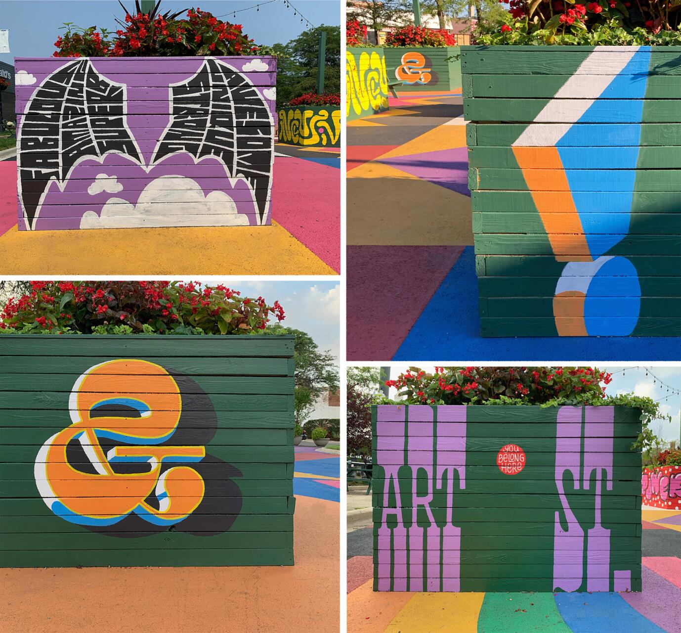 Colorful street art on planters with floral arrangements. Designs include bold lettering and abstract shapes in vibrant hues of purple, orange, blue, and green on a colorful pavement.