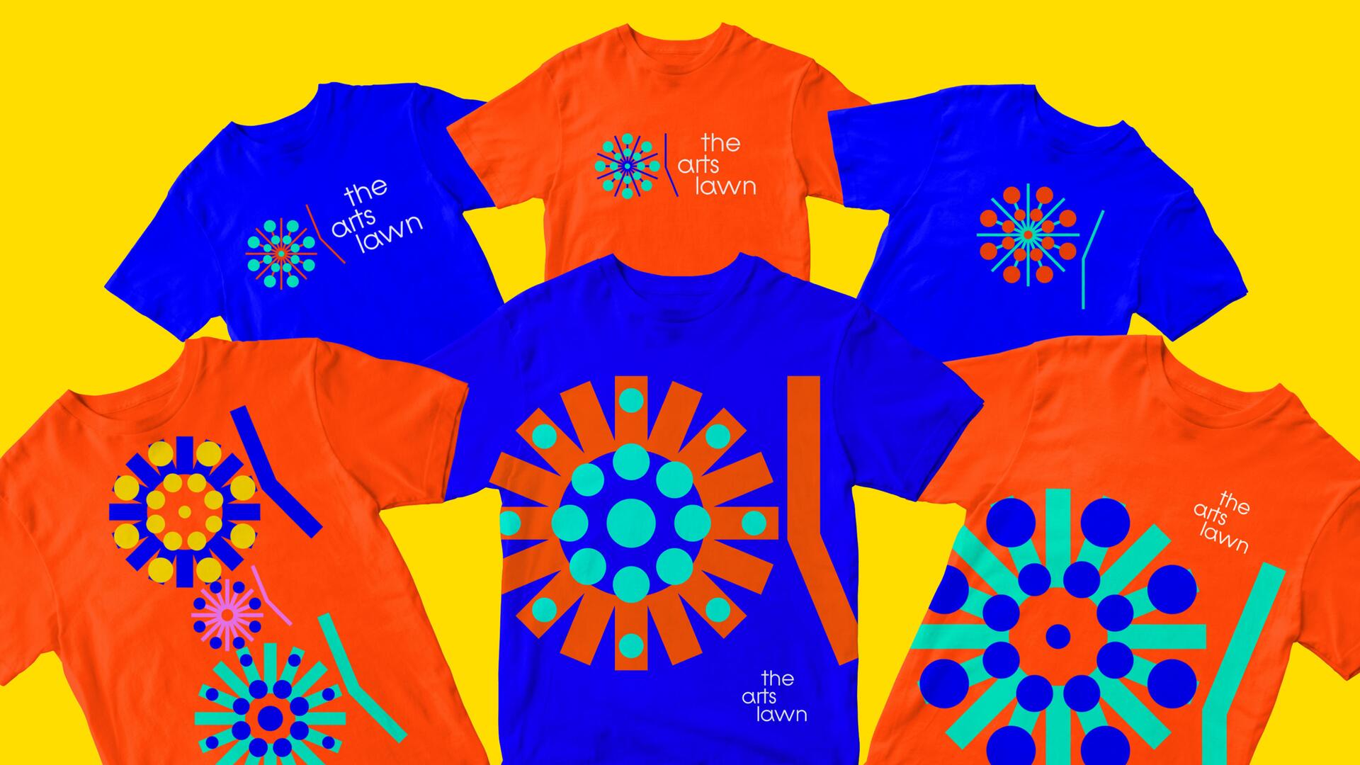 Colorful t-shirts with geometric designs featuring circles and lines in shades of blue, orange, and green on a bright yellow background.