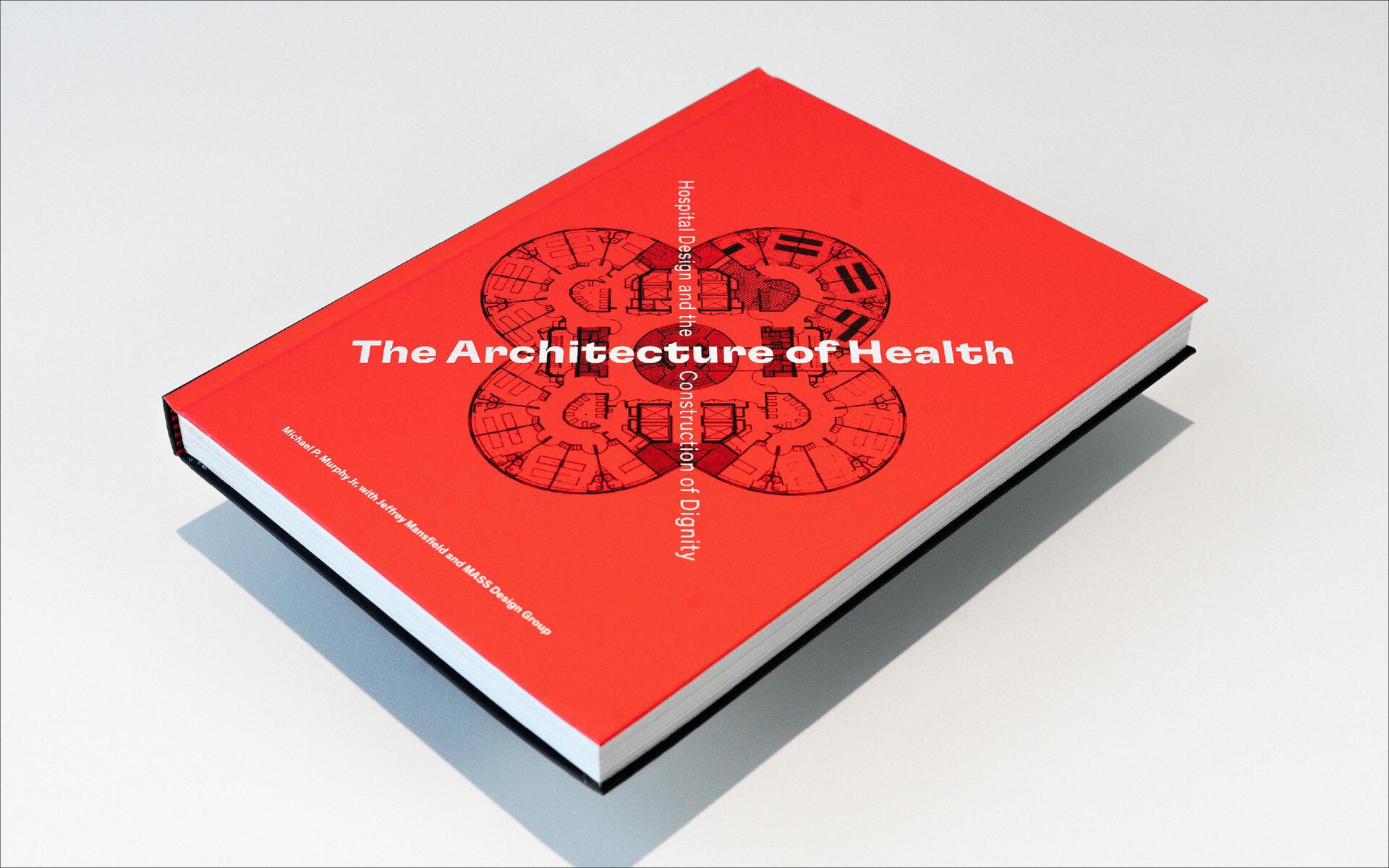 Red book titled "The Architecture of Health" on a light surface, featuring a circular architectural design sketch on the cover.
