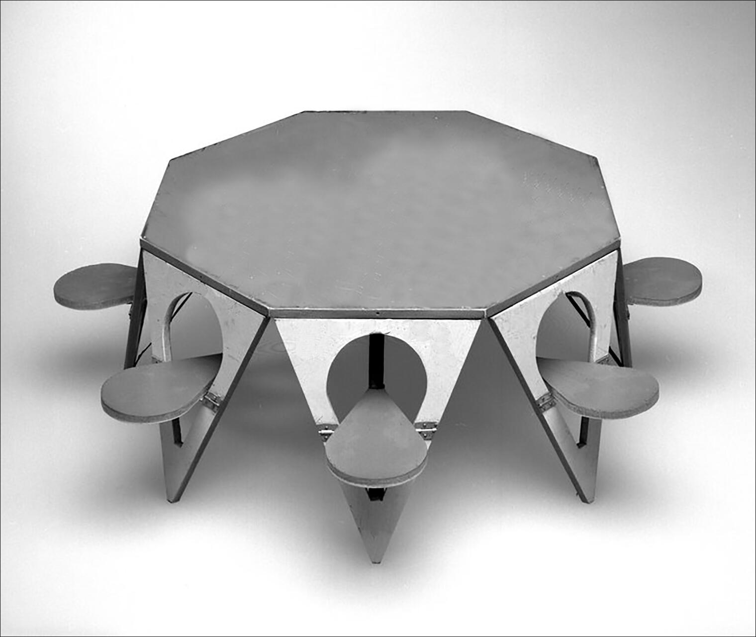 Octagonal metal table with built-in seats, featuring triangular support structures and circular cutouts, set against a plain background.