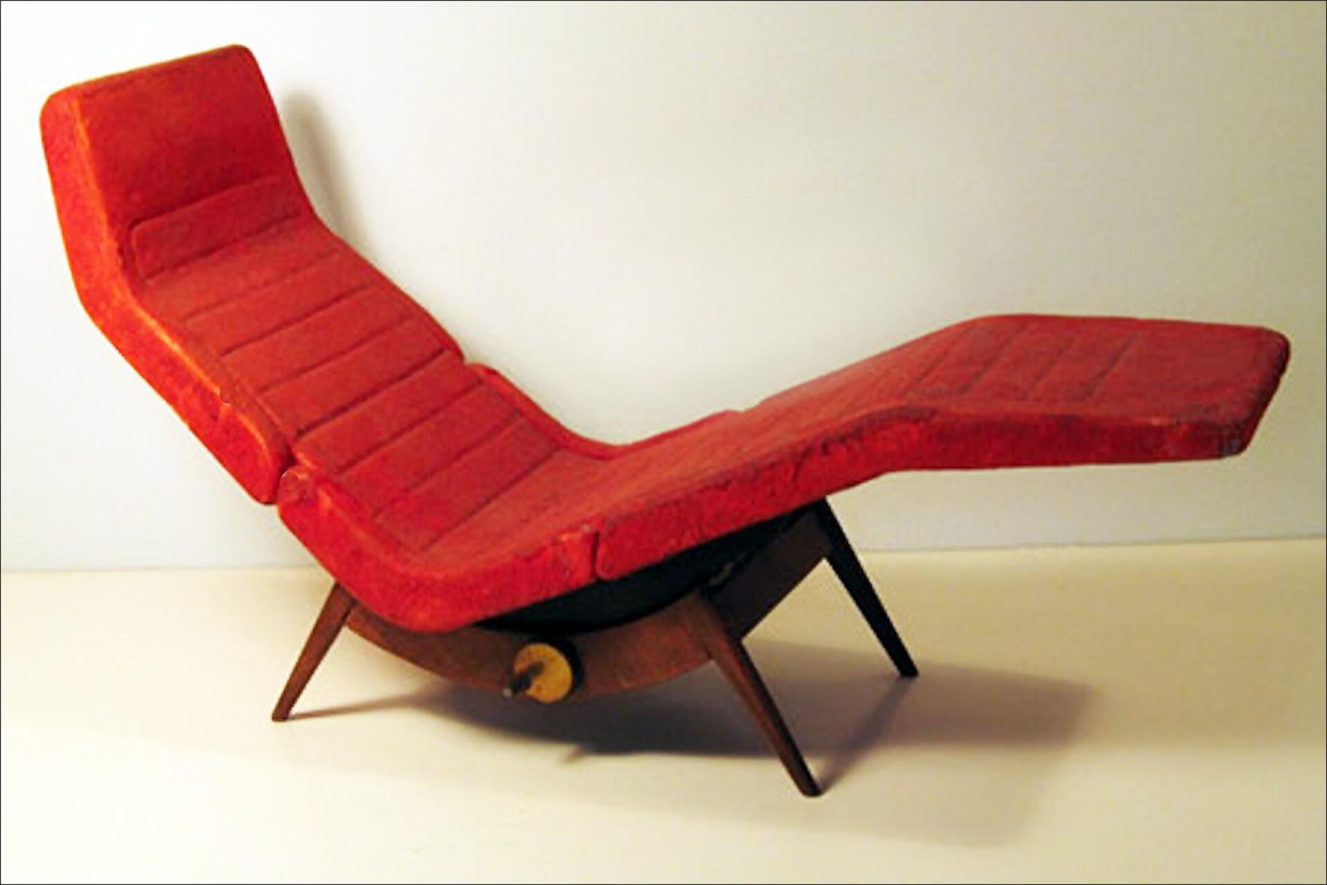 Red vintage chaise lounge with a segmented cushion design and angled wooden legs, set against a plain background.
