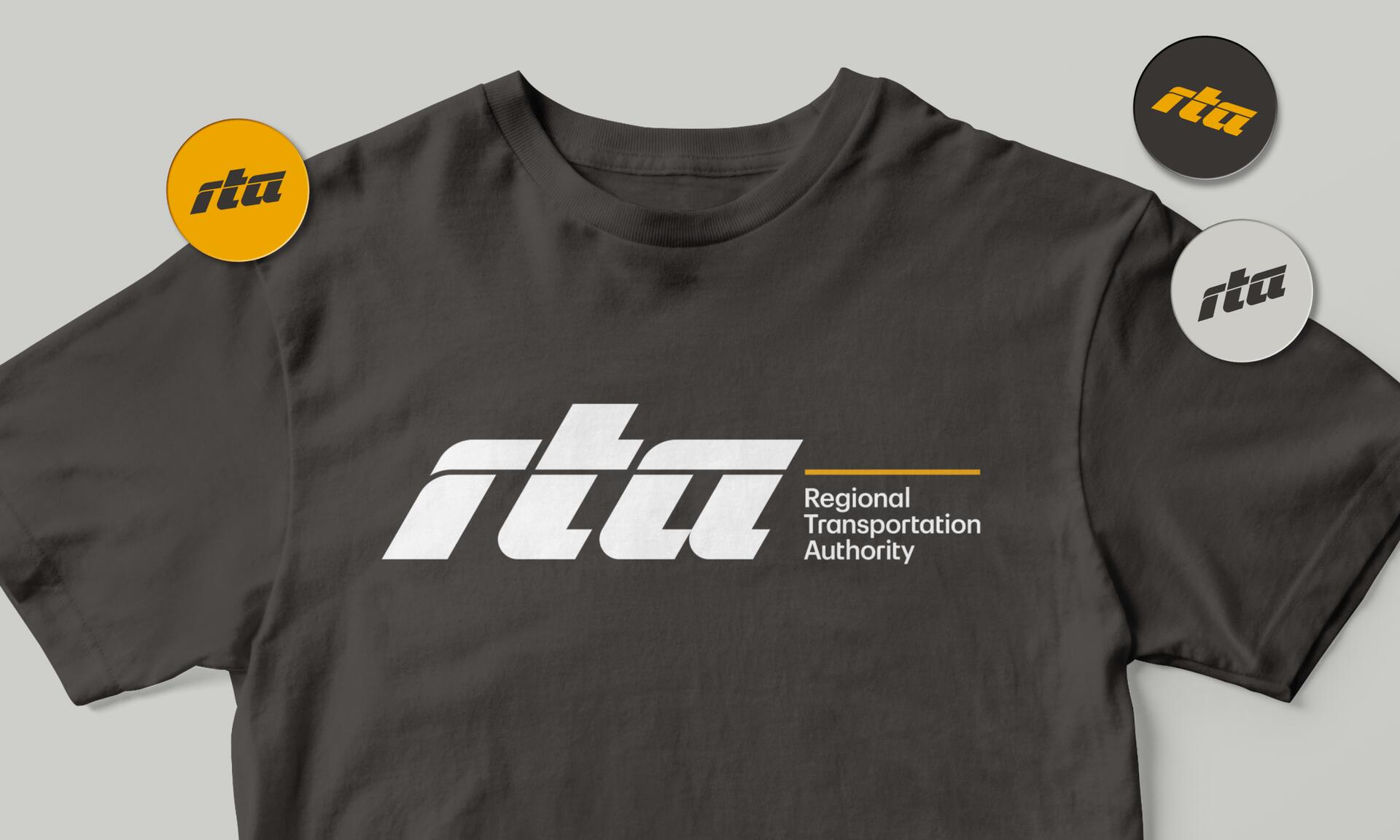 Gray T-shirt featuring "rta Regional Transportation Authority" logo in white, with three logo variations displayed in circular badges—orange, black, and gray.