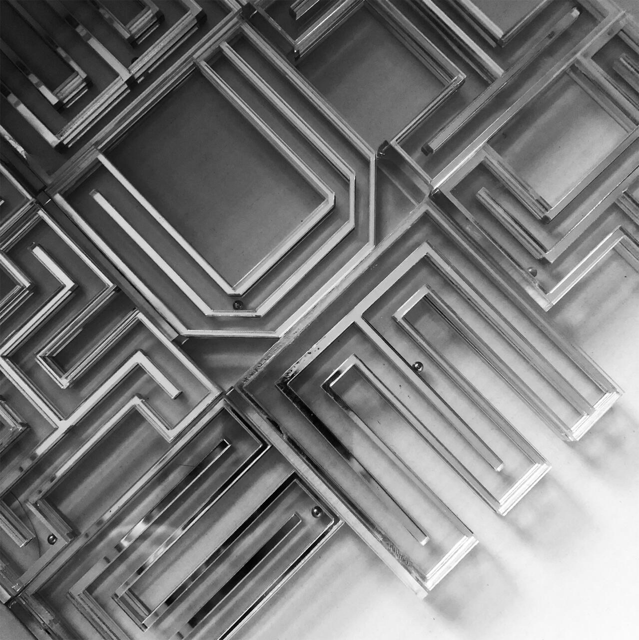 Intricate black and white geometric patterns with layered, angular shapes creating a maze-like appearance.