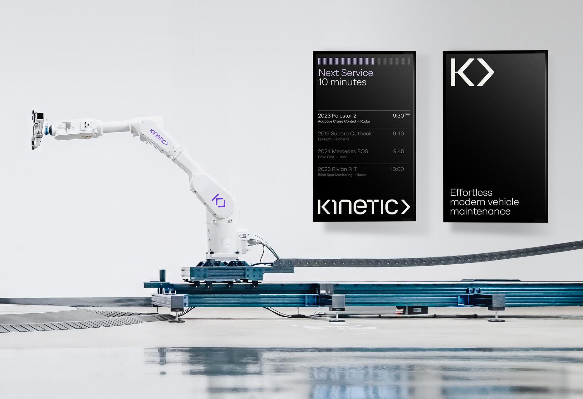 Robotic arm in a clean, modern workshop setting, positioned near two sleek digital displays with the word "KINETIC" and vehicle service details.