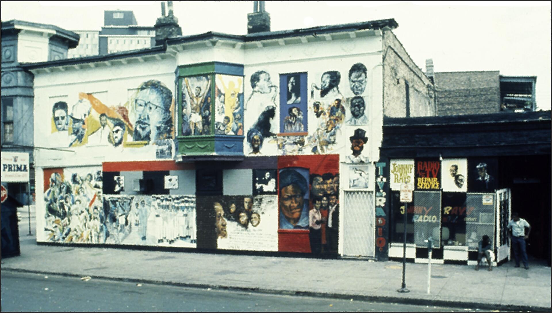 Building facade adorned with colorful murals depicting various people and scenes. Storefront displays signage with text and images. A person stands by the door, and a child with a doll is nearby on the sidewalk. Urban environment in the background.