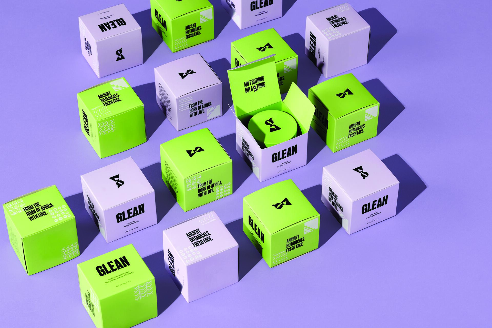 Green and white product boxes with words like "Glean" on a purple background, arranged in a grid pattern. One box is open, revealing a container inside.