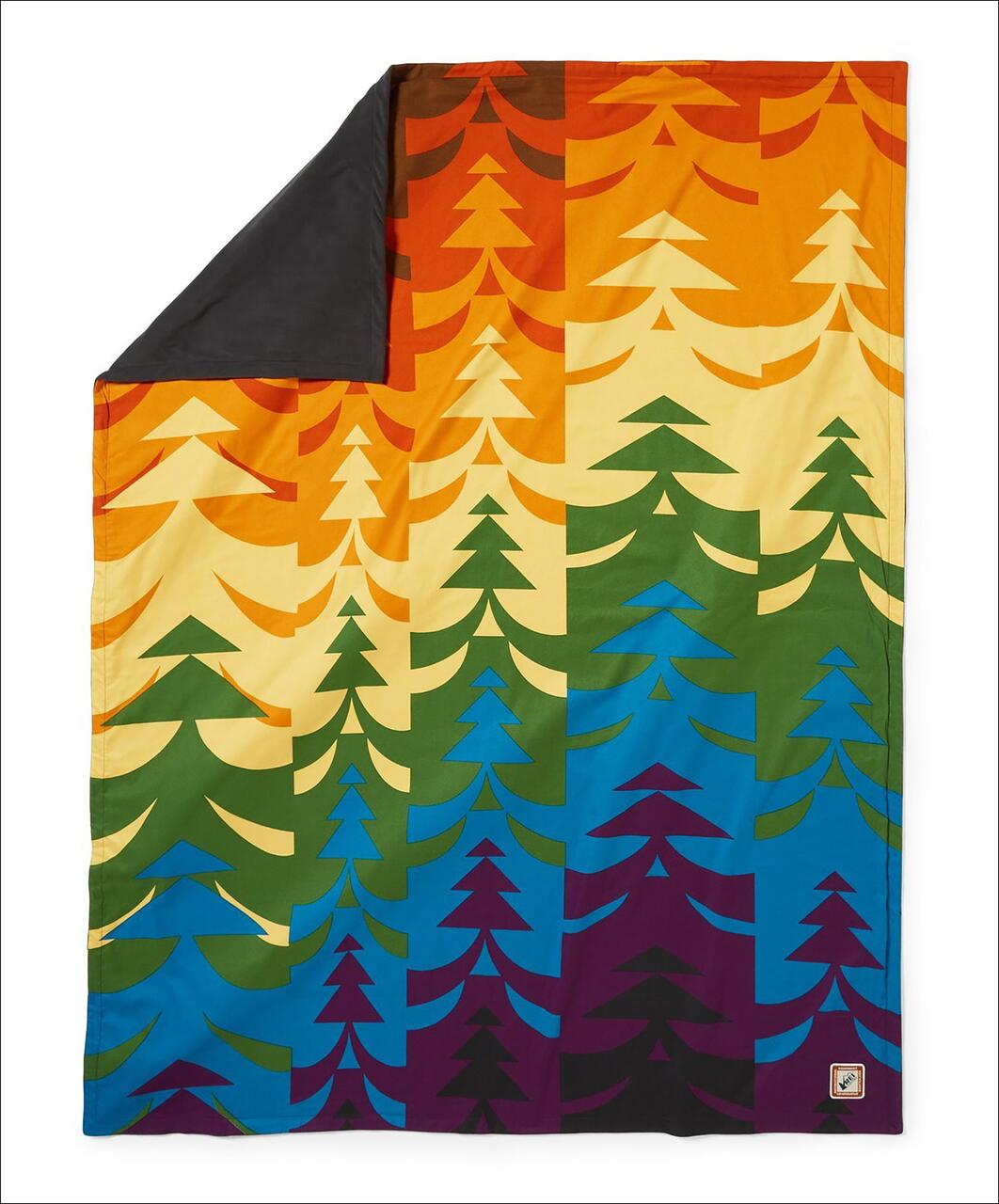 Colorful blanket with stylized tree patterns in orange, yellow, green, blue, and purple, featuring a dark gray corner.
