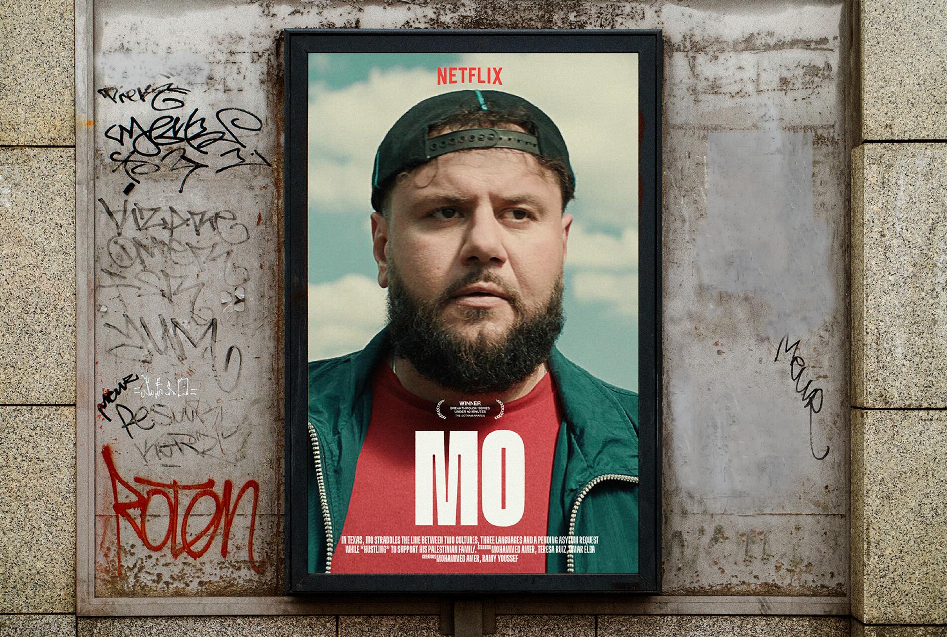 Netflix poster with a bearded man in a black cap and green jacket against a cloudy sky backdrop, surrounded by graffiti on a weathered wall. The text reads "Mo."