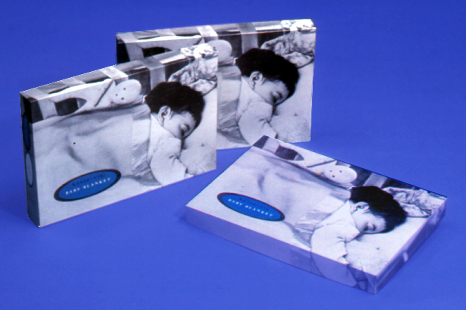 Three packages with black-and-white photos of a sleeping baby, set against a blue background.