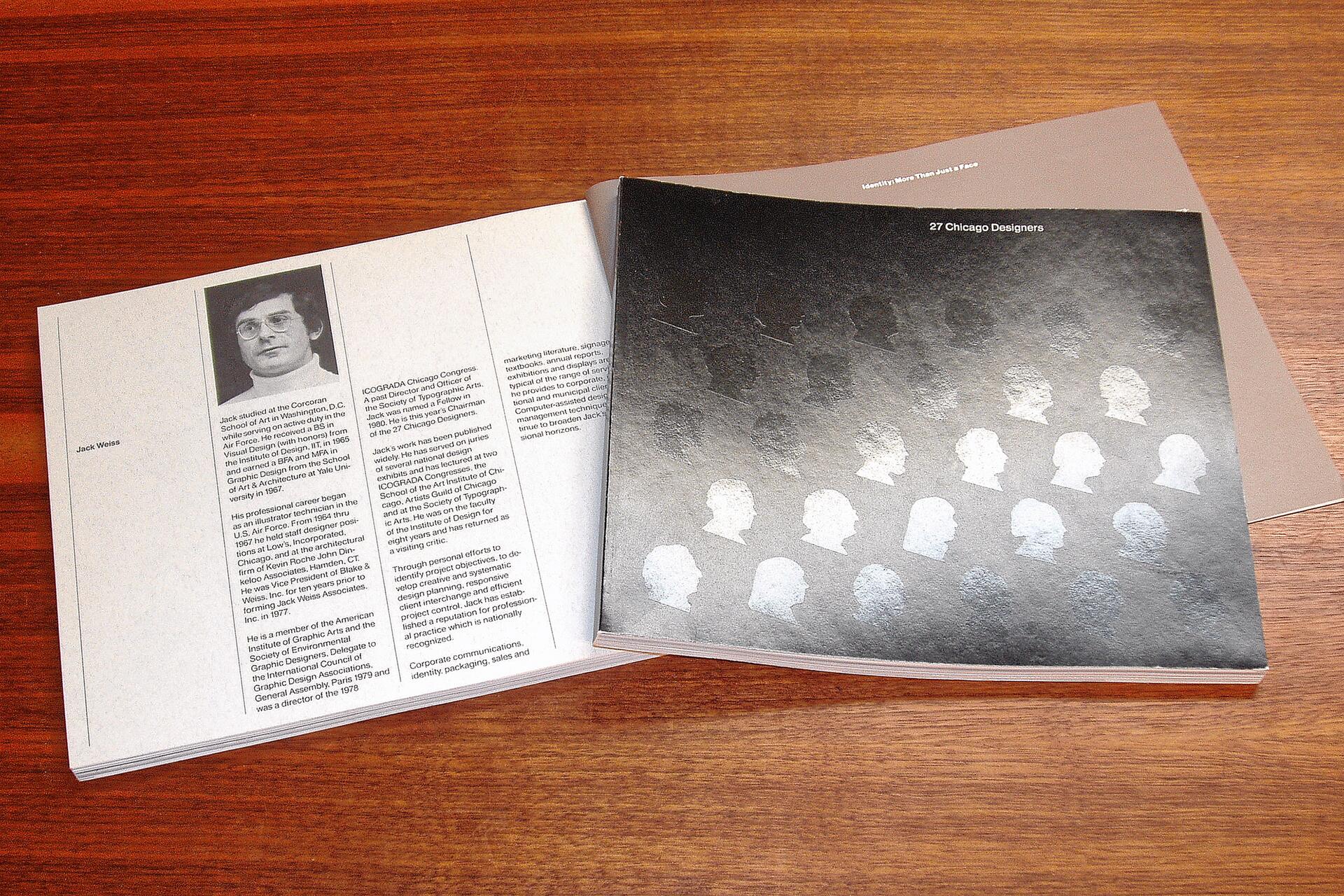 Open book on a wooden table, featuring a biography page with a black-and-white photo on the left, and a glossy black cover with white silhouette profiles arranged in rows on the right.