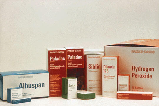 Various pharmaceutical product boxes with labels from the brand Parke-Davis are displayed, including Albuspan, Paladac, Surital, Sibilin, Dilantin 125, and Hydrogen Peroxide. The boxes vary in size and color.