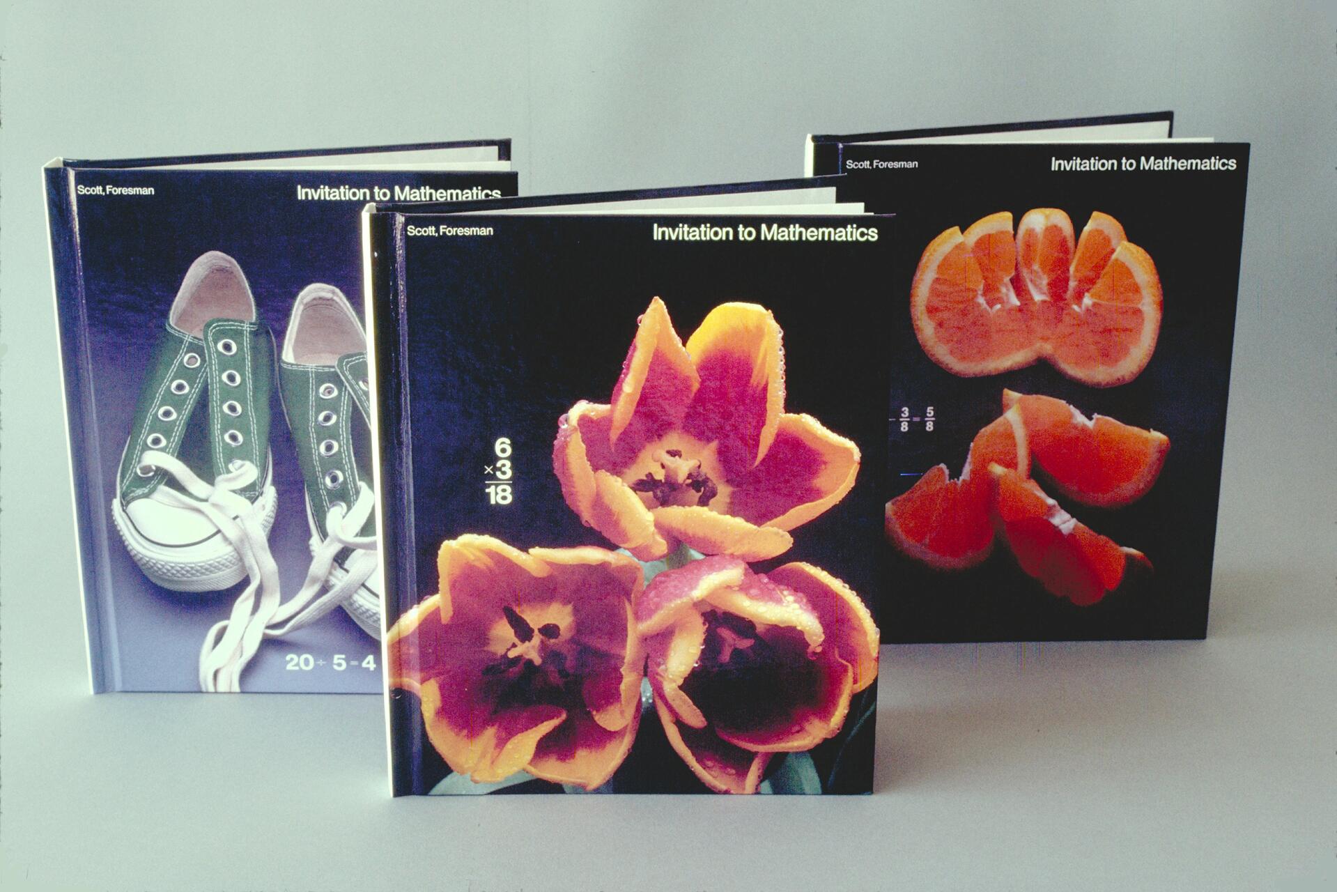 Three math textbooks with artistic covers; one with green sneakers and laces, another with colorful tulips, and the third with sliced oranges, each displaying mathematical equations.