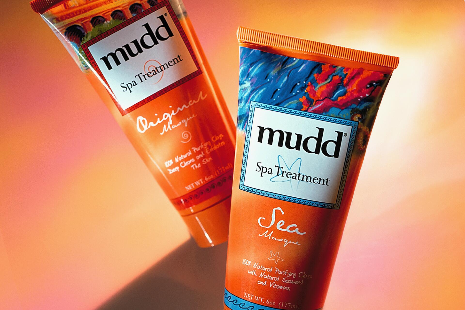 Two tubes of Mudd Spa Treatment face masks against a warm gradient background. The left tube is labeled "Original" in orange, and the right tube is labeled "Sea" with a blue and orange design. Both tubes emphasize natural purifying clays.