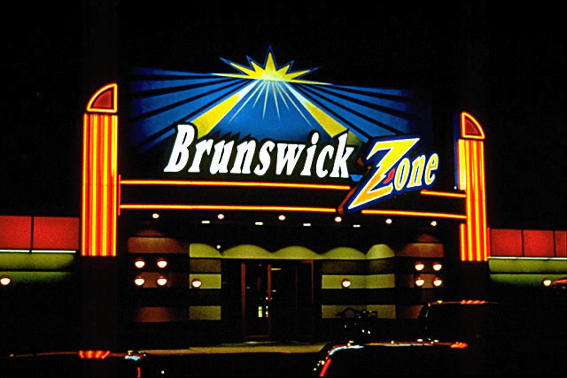 Brightly lit Brunswick Zone bowling alley sign at night, featuring bold red, blue, and yellow neon colors with geometric accents.