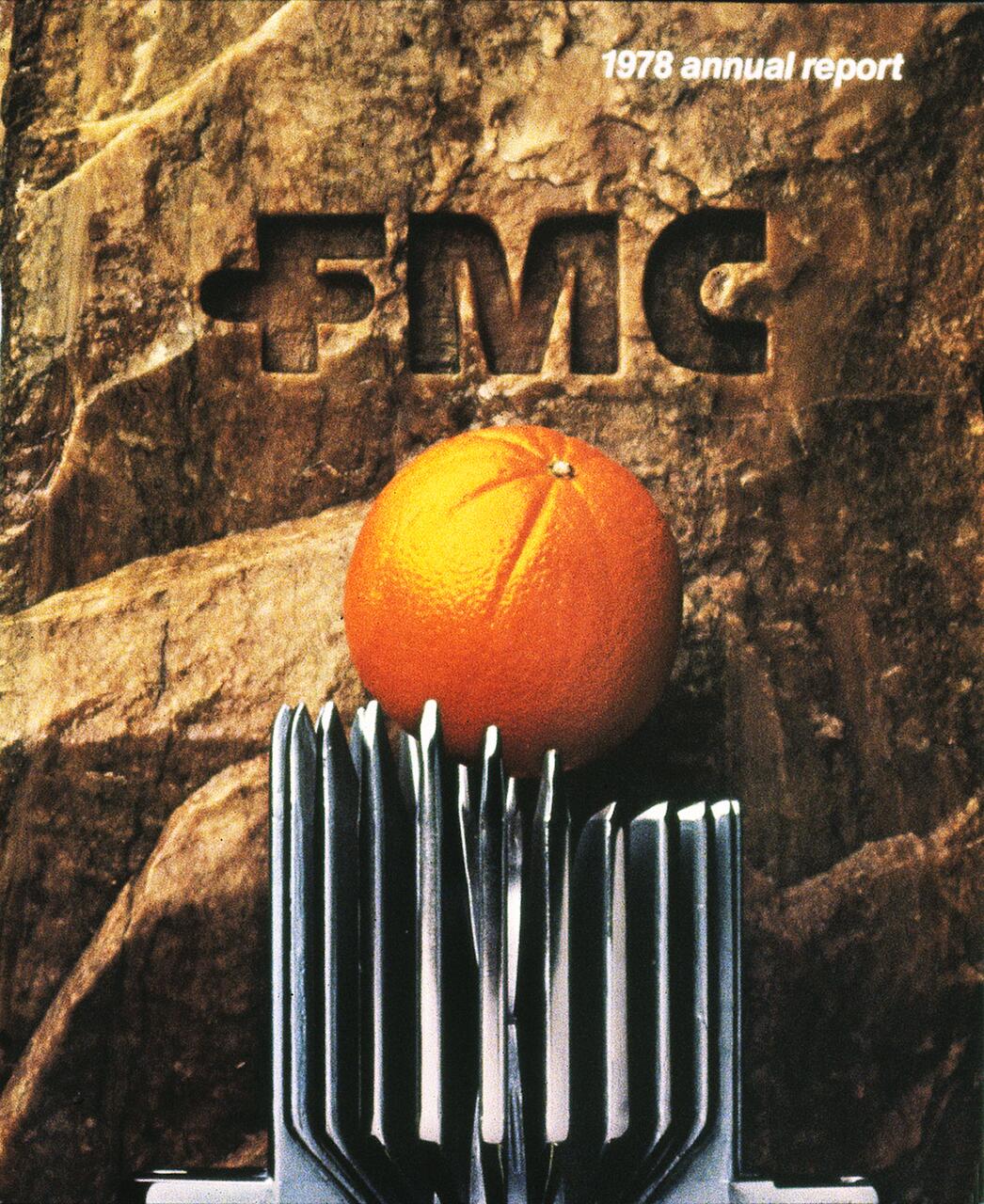 Orange resting on a metallic structure, set against a textured rock background with "FMC" carved into it.