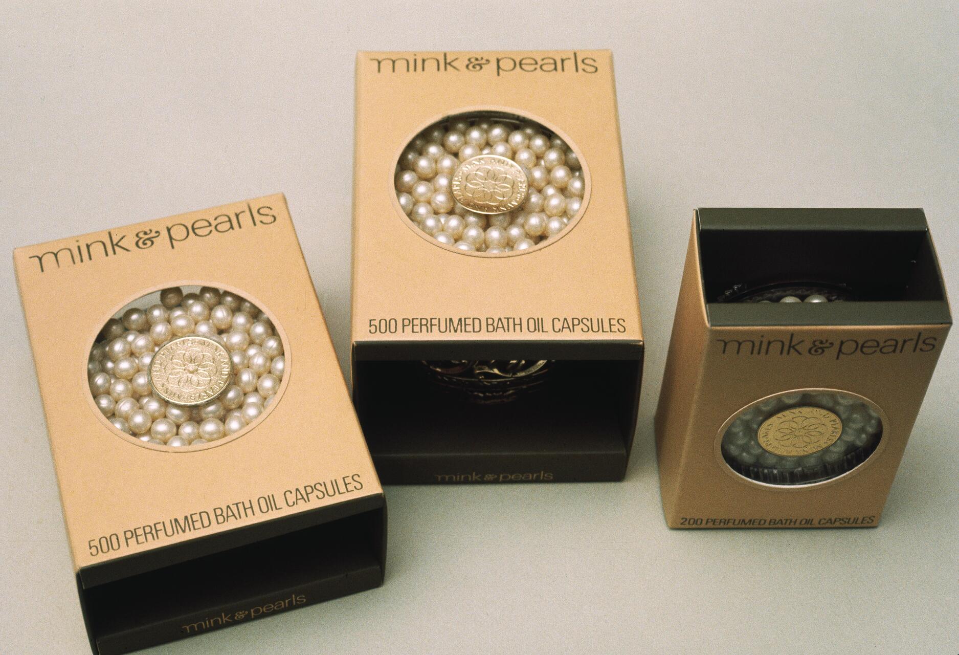 Three boxes of mink & pearls perfumed bath oil capsules in beige packaging, featuring a circular window showing pearl-like capsules inside. Two larger boxes indicate 500 capsules, and one smaller box indicates 200 capsules.