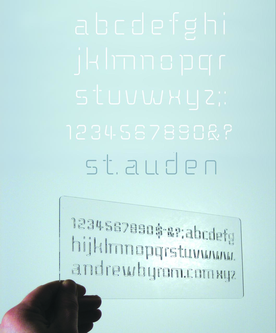 A hand holds a transparent stencil displaying an alphabet and numbers. The words "st.auden" appear in a subtle, modern font against a light blue background.