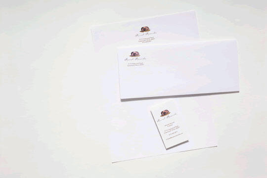 Stationery set with envelopes and a business card, each featuring a printed logo with a brown and gold design on white paper, arranged neatly on a white background.