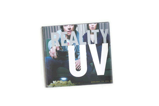 Spiral-bound graphic design book cover titled "Reality UV" featuring two people on a couch, reaching forward, with a bold typographic layout.