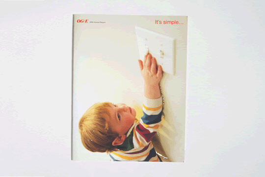 Toddler in a striped shirt reaching up to touch a light switch on a plain wall.