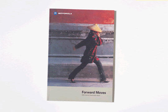 A person wearing a straw hat and traditional attire walks briskly in front of a stone wall. The setting is urban, with a contrast of muted gray and bright red colors. The text "Forward Moves" is visible at the bottom.