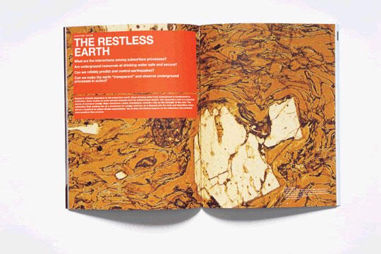 Open magazine showing a spread with the left page featuring a red header titled "The Restless Earth" and smaller text below. The right page displays an abstract, geological pattern with brown and beige swirls resembling a textured rock surface.