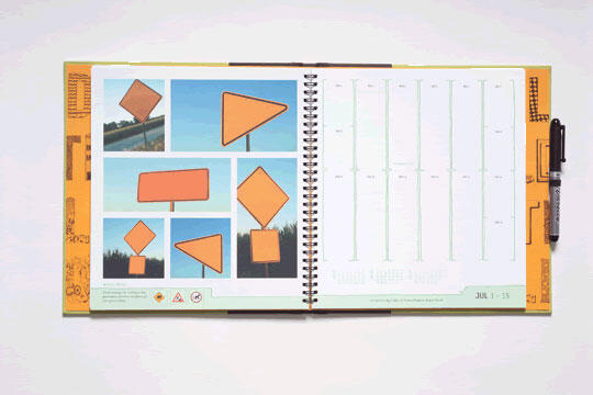 Open spiral notebook displaying photos of orange traffic signs on left, a calendar on the right, and a pen tucked at the edge.