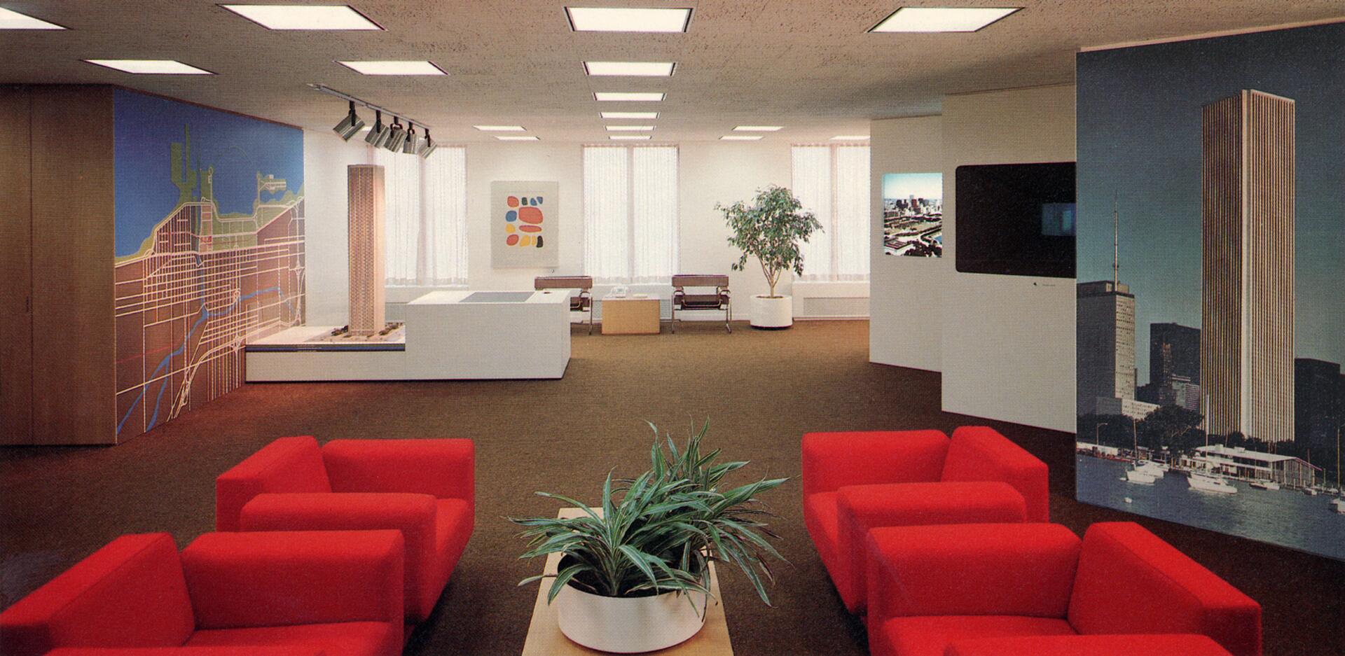 Modern office with red chairs, a central table with a plant, and large architectural displays. Walls are decorated with a city map and a tall building image. Soft lighting and a potted tree add to the ambiance.