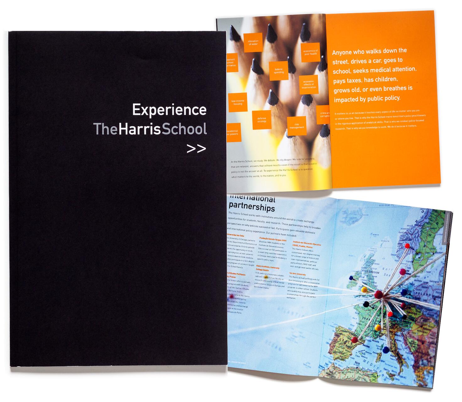 Black cover with "Experience The Harris School" in white. Next to it, an open brochure with pages showing a sharpened pencil pattern and global map with colored pins connected by strings, reflecting themes of education and international partnerships.