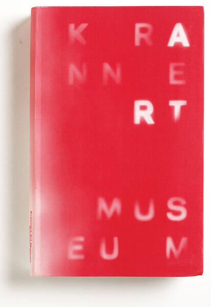 Red book cover with white blurred letters spelling "Krannert Art Museum" vertically.