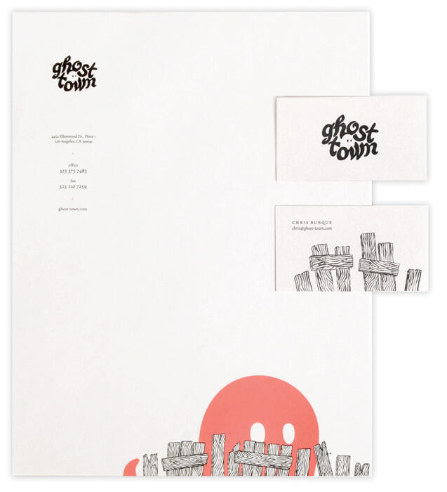 White stationery set with "ghost town" logo, featuring a red ghost illustration peeking from the bottom. Includes a business card with wooden plank design and contact information.