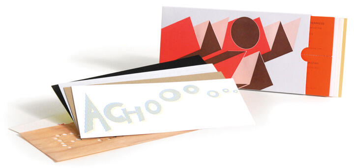 Colorful greeting cards displayed, one featuring the word "ACHOOO" in large letters. The cards have abstract geometric designs in vibrant shades of red, brown, and orange.