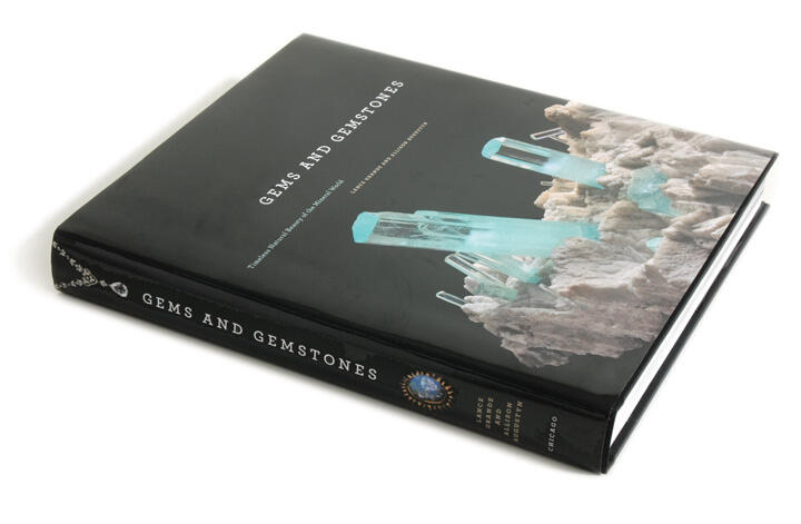 Black hardcover book titled "Gems and Gemstones" featuring an image of turquoise crystals emerging from grey mineral formations.