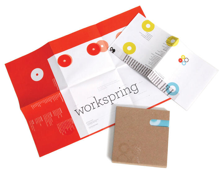 Two colorful folded brochures and a brown booklet on a white surface, featuring abstract circular designs and the word "workspring" visible on the red and white brochure.