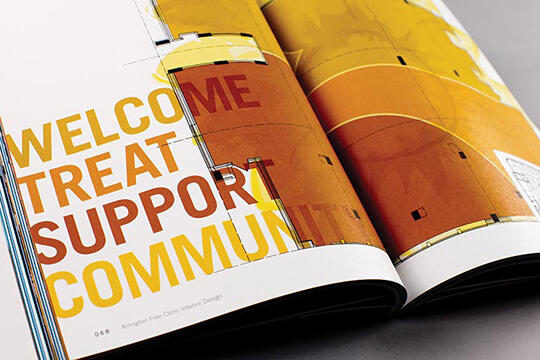 Open magazine with bold text in yellow and red reading "WELCOME TREAT SUPPORT COMMUNITY" alongside abstract geometric designs in yellow and orange tones.
