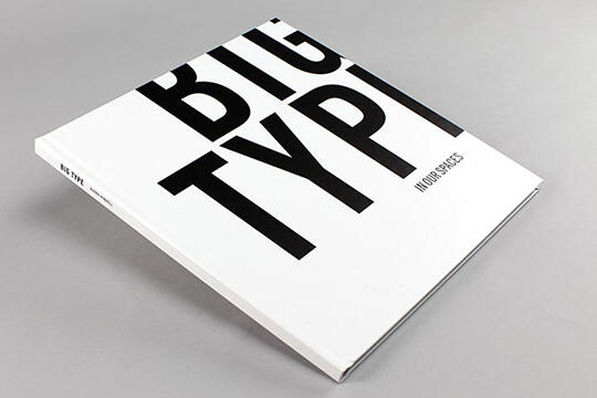 Square book with large black text "BIG TYPE" on a white cover, titled "BIG TYPE" and subtitled "INDOOR SPACES." The book rests on a light gray surface.