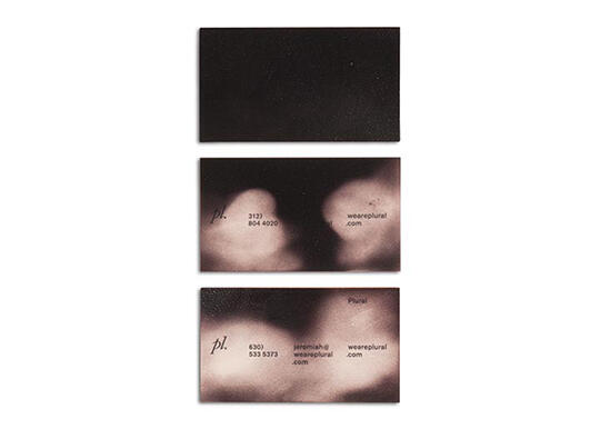 Three black business cards with faint, cloud-like patterns in white and black text, including contact details and the word "plural."